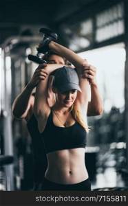 Athletic fitness woman pumping up muscles with dumbbells, Fit woman working out with trainer at the gym