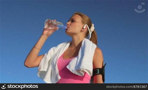 Athletic girl drinks water after running and exercising outdoors