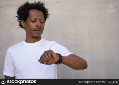 Athletic man checking time on his smart watch while work out outdoors. Sport and healthy lifestyle concept.