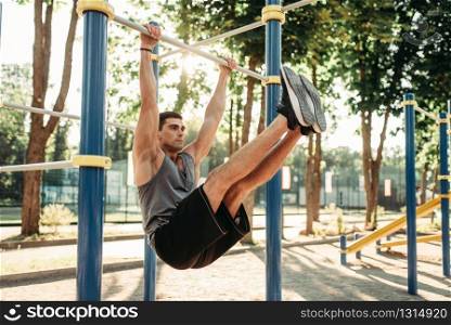 Athletic man doing exercise on press using horizontal bar, outdoor fitness workout. Strong sportsman on sport training in park. Man doing exercise on press using horizontal bar