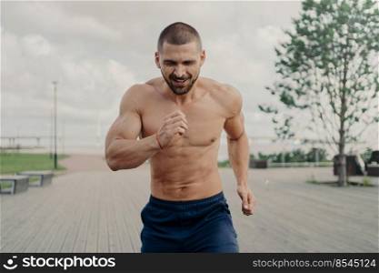 Athletic motivated male jogger takes part in running marathon, has aim to come first on finish, exercises outdoors and trains endurance. Active healthy sportsman has fitness training in morning.