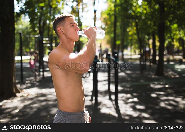 Athletic sport man drinking water from a bottle. Outdoor fitness.. Athletic sport man drinking water from a bottle. Outdoor fitness