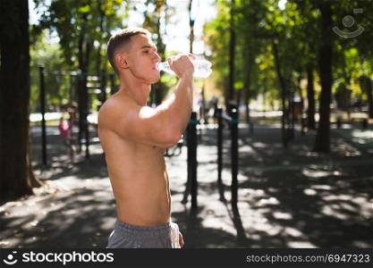 Athletic sport man drinking water from a bottle. Outdoor fitness.. Athletic sport man drinking water from a bottle. Outdoor fitness