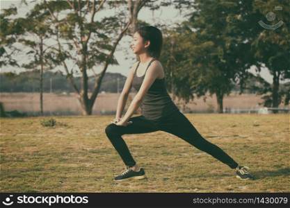 Athletic woman asian warming up and Young female athlete sitting on an exercising and stretching in a park before Runner outdoors, healthy lifestyle concept,soft focus