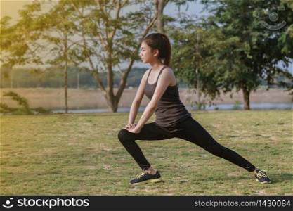 Athletic woman asian warming up and Young female athlete sitting on an exercising and stretching in a park before Runner outdoors, healthy lifestyle concept