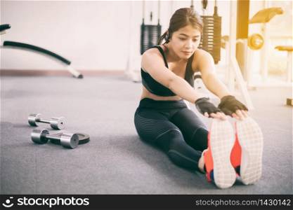 Athletic woman asian warming up and Young female athlete sitting on an exercising and stretching in a gym, healthy lifestyle concept