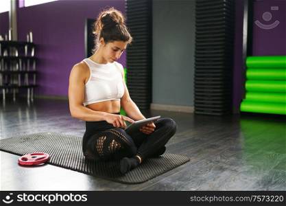 Athletic woman consulting her training on her smart phone at the gym. Woman consulting her training on her smartphone
