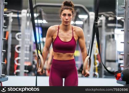 Athletic woman doing some pull up exercises in the gymnastic rings in a gym. Athletic woman doing some pull up exercises in the gymnastic rings