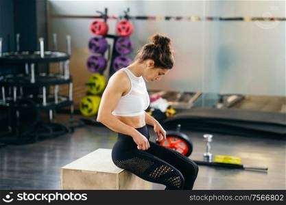 Athletic woman doing squats on box as part of exercise routine. Caucasian female doing box jump workout at gym.. Athletic woman doing squats on box at the gym