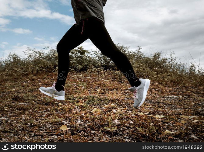 Athletic woman running on forest trail. Female runners running in nature in the morning. Workout Healthy lifestyle concept. close-up legs with running shoes.