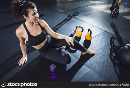 athletic woman sitting near exercise equipments gym
