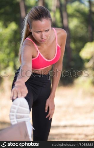 athletic woman stretching he legs before workout outside