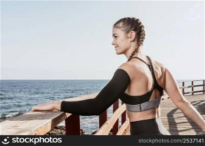 athletic woman stretching outdoors by beach with copy space