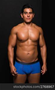 Athletic young man bare chested in blue briefs