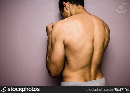 Athletic young man facing a wall