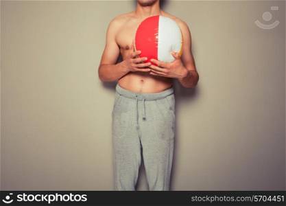 Athletic young man is holding a beach ball