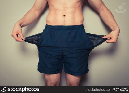 Athletic young man is showing his empty pockets