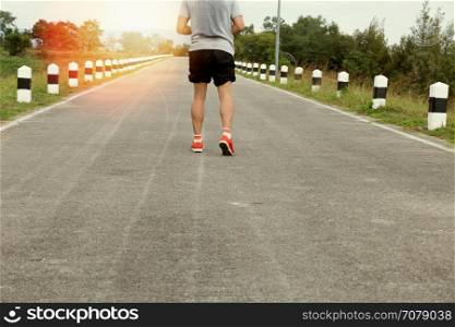 athletic young man jogging, running on road in the park. Healthy lifestyle