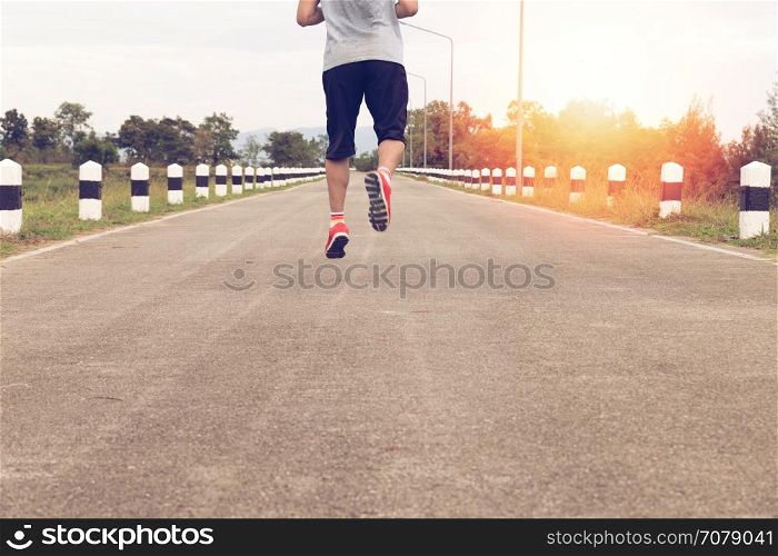 athletic young man jogging, running on road in the park. Healthy lifestyle