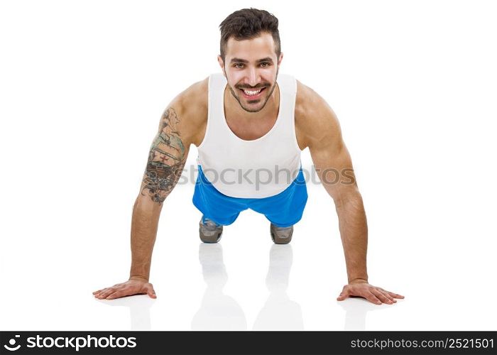 Athletic young man smiling and making pushups, isolated over a white background