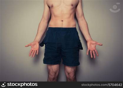 Athletic young man with empty pockets cannot afford to go to the gym