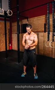 Athletic young smiling man prepares to do functional training without a shirt