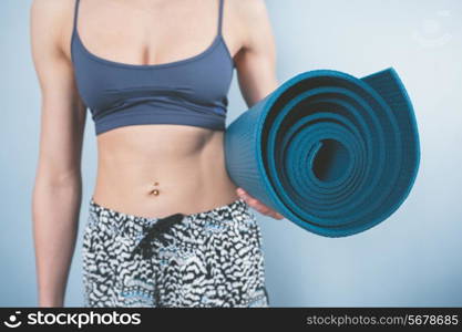 Athletic young woman is holding a yoga mat