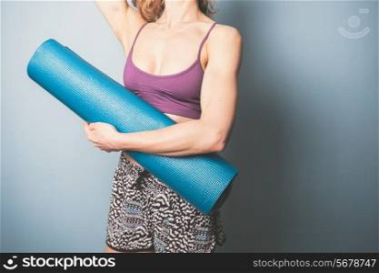 Athletic young woman is holding a yoga mat