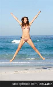 Athletic Young Woman Jumping On Sandy Beach On Holiday Wearing Bikini