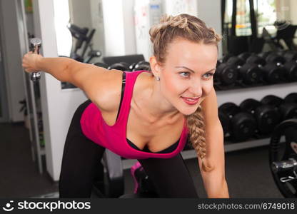 Athletic young woman training with dumbbell in the gym