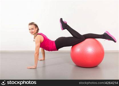 Athletic young woman with red ball on the floor