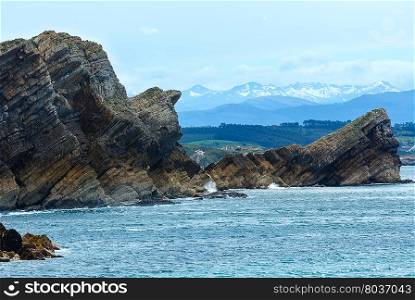 Atlantic Ocean rocky coastline landscape (Spain) and mountains with snow in background .