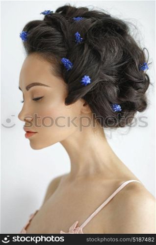Atmospheric art-fashion portrait of beautiful young woman with blue muscari in her hair. Spring vibes. Summer freshness
