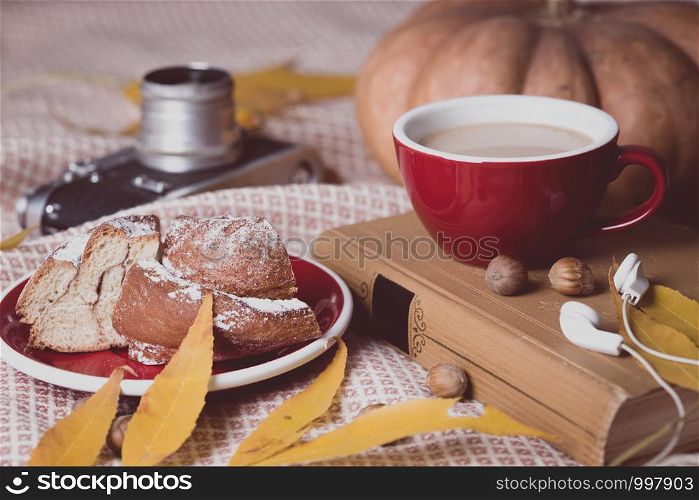 atmospheric autumn background cup of coffee, bun, pumpkin, apples, book, headphones, retro camera