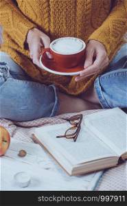 atmospheric autumn background. girl holds cup of coffee. bun, pumpkin, apples, book, headphones, retro camera in frame