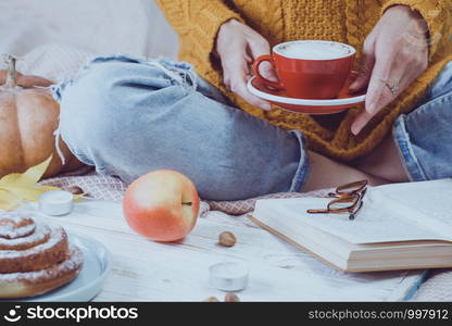 atmospheric autumn background. girl holds cup of coffee. bun, pumpkin, apples, book, headphones, retro camera in frame