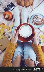 atmospheric autumn background. girl holds cup of coffee. bun, pumpkin, apples, book, headphones, retro camera in frame