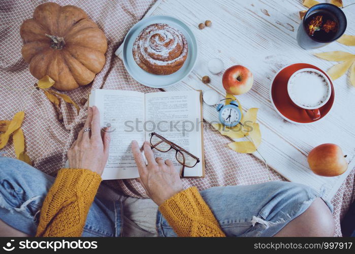 atmospheric autumn background. girl holds cup of coffee. bun, pumpkin, apples, book, headphones, retro camera in frame