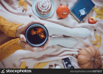 atmospheric autumn background. girl holds cup of tea. bun, pumpkin, apples, book, headphones, retro camera in frame