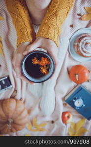 atmospheric autumn background. girl holds cup of tea. bun, pumpkin, apples, book, headphones, retro camera in frame