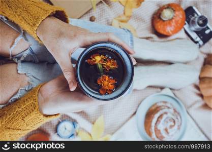 atmospheric autumn background. girl holds cup of tea. bun, pumpkin, apples, book, headphones, retro camera in frame