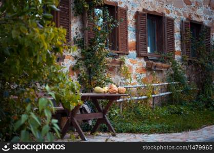 atmospheric morning on a farm in the village in the mountain. old beautiful house, windows with shutters, a table with pumpkins in the foreground
