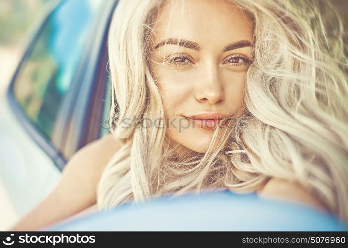 Atmospheric outdoors fashion portrait of beautiful blonde in car on the beach. Summer trip. Summer vibes