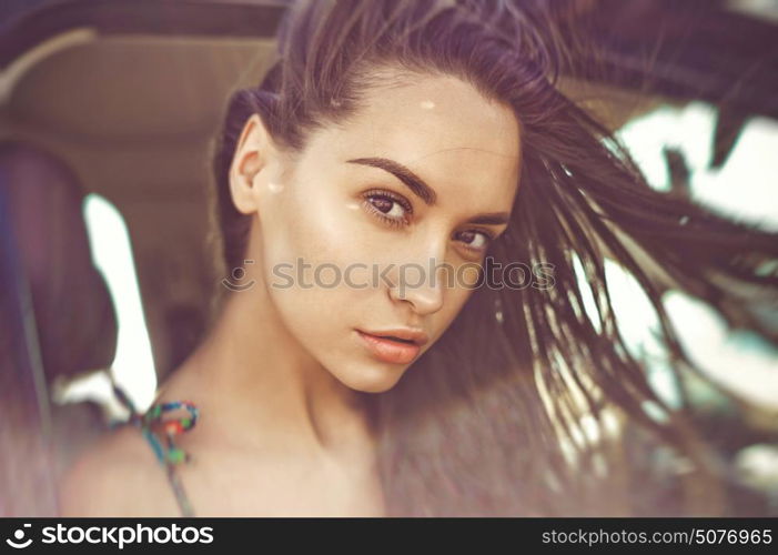 Atmospheric outdoors fashion portrait of beautiful brunette woman in car on the beach. Summer trip. Summer vibes