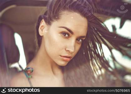 Atmospheric outdoors fashion portrait of beautiful brunette woman in car on the beach. Summer trip. Summer vibes