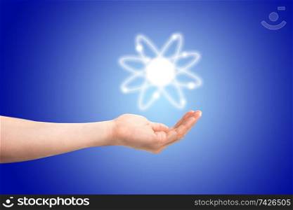 Atom structure model in a hand with nucleus and electrons, technological concept of nuclear power. Flat illustration on blue background