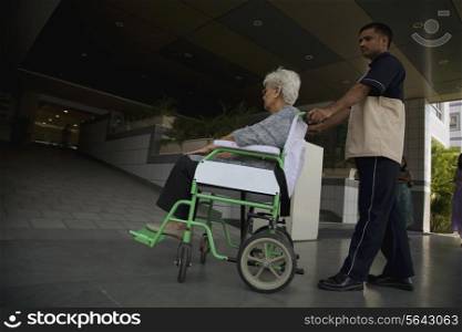 Attendant helping patient on wheelchair