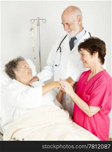Attentive doctor and nurse caring for an elderly hospital patient.