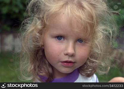 attentive mischievous little girl in garden (with water drops in hair)