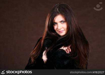 attracive young woman in a fur coat brown background